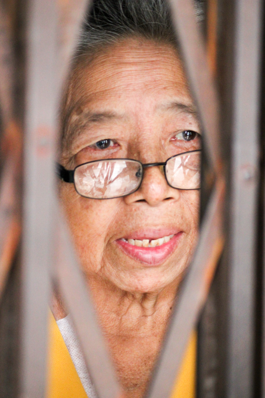 Ph. Monica Costa, Naturalistic Photography - Asian grown woman behind her home gate Ph. Monica Costa, Naturalistic Photography - Asian grown woman behind her home gate